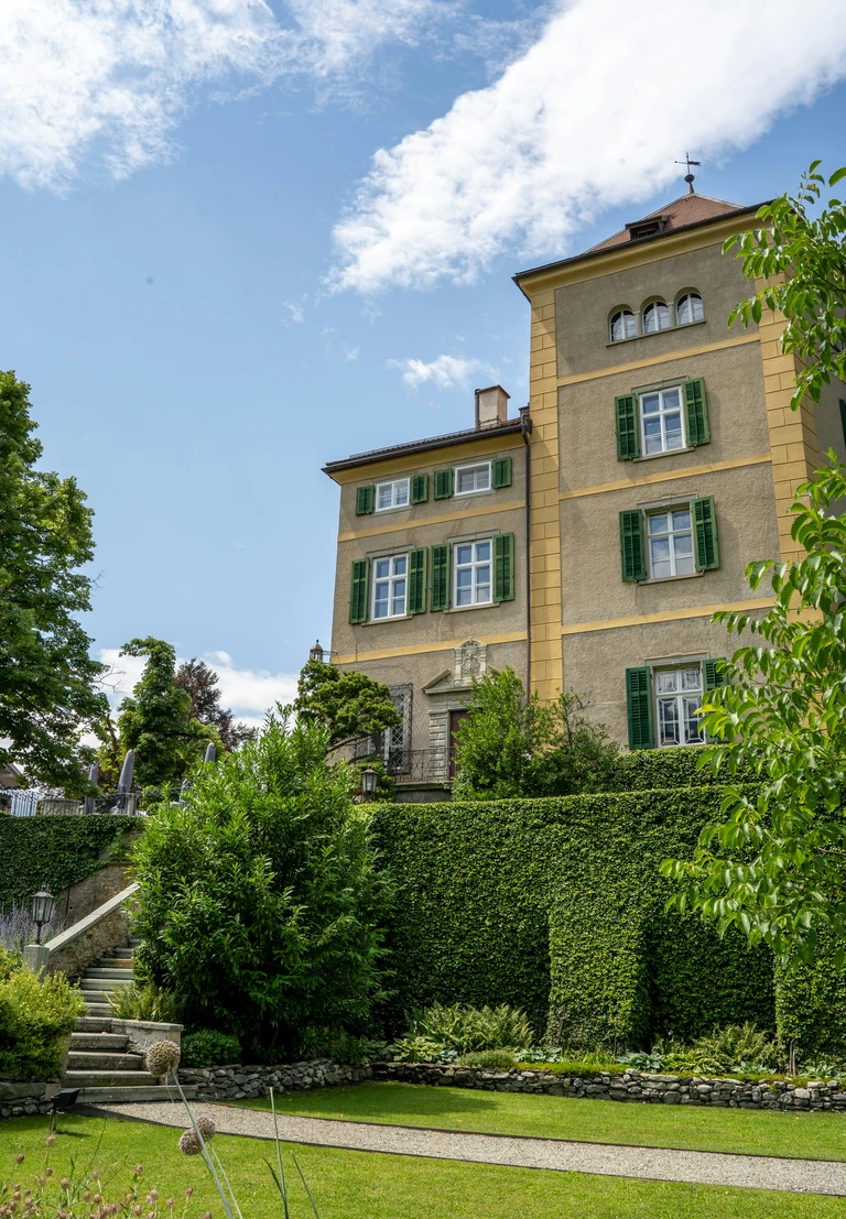 Bâtiment ancien entouré d'un parc, en pleine journée.