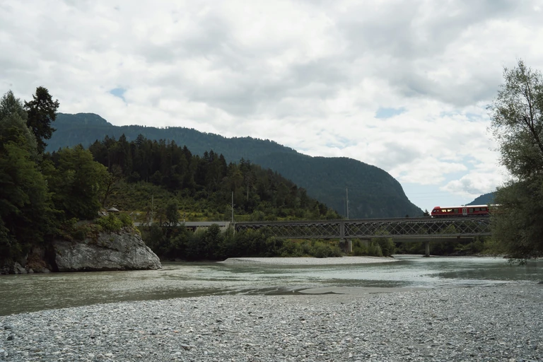 Pont ferroviaire au-dessus d'une rivière, en montagne.